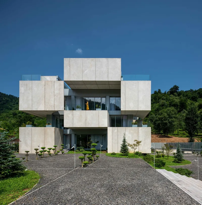 Front elevation showing the symmetrical concrete facade with projecting balconies and gravel approach path