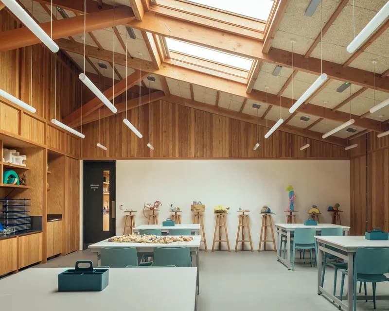 Workshop space with cork ceiling panels, timber framing and wooden easels arranged along a whiteboard wall