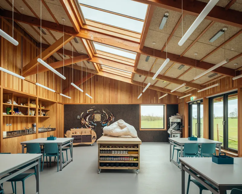 Classroom interior with vertical timber walls, exposed rafter ceiling, and continuous skylights above work tables