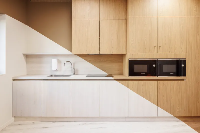Kitchen with light oak cabinetry and white lower units under a diagonal shaft of sunlight