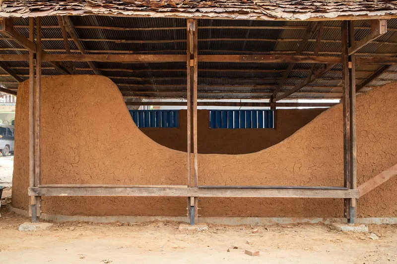 Exterior elevation reveals the fluid geometry of rammed earth walls under a lightweight roof.