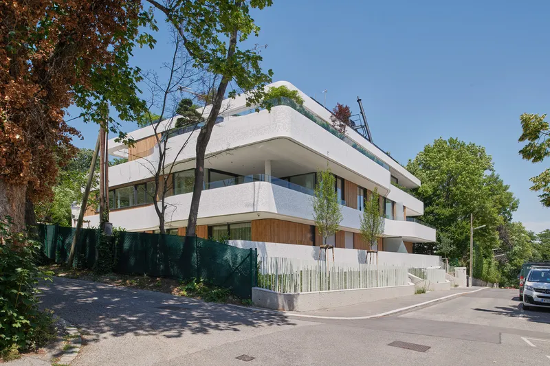 Street corner view of the building surrounded by mature trees in summer foliage