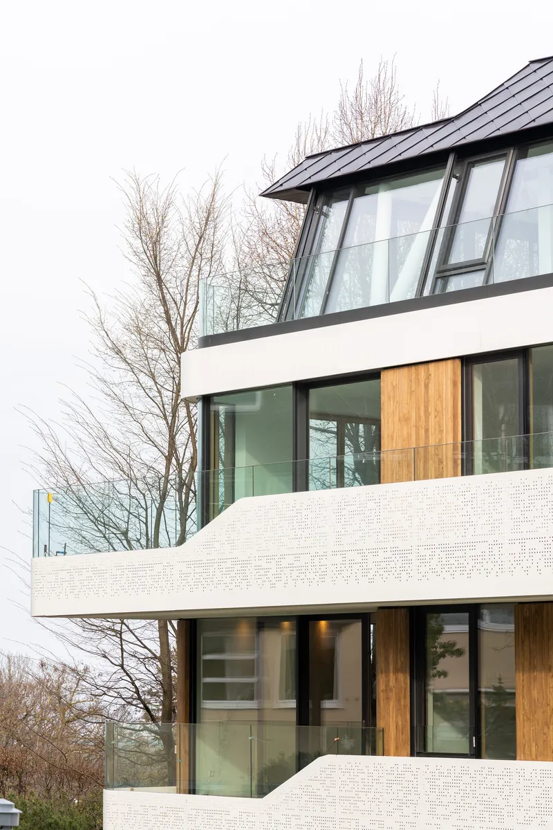 Stacked white brick terraces with floor-to-ceiling glass and timber paneling beside bare winter trees