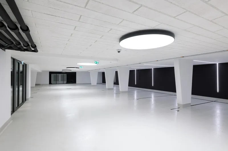 Underground parking garage with white epoxy floor, angled columns, and black recessed lighting panels