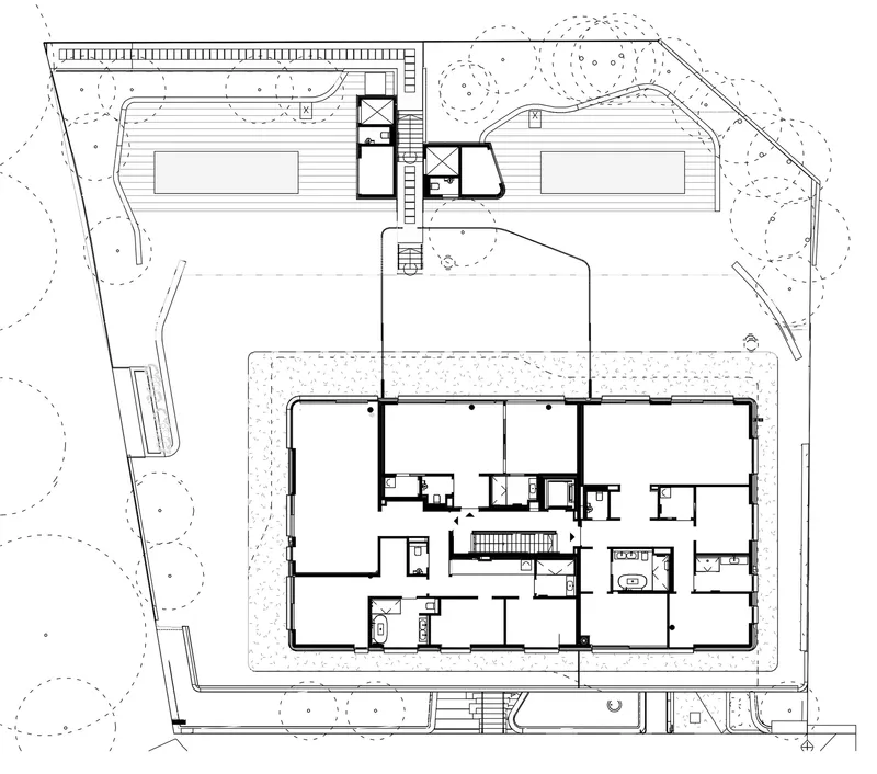Site plan drawing showing two rectangular buildings with a connecting core and surrounding landscape with trees