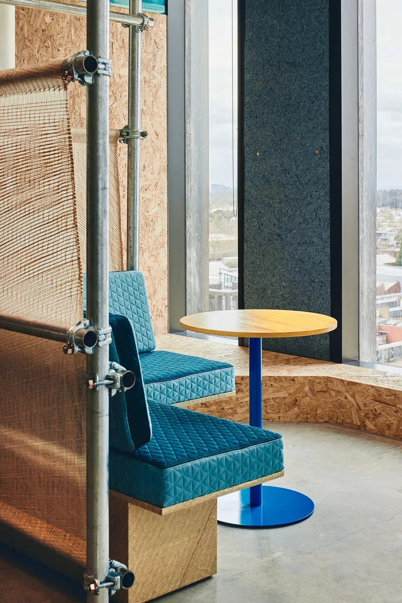 Window seating nook with upholstered benches and round table overlooking the urban roofscape