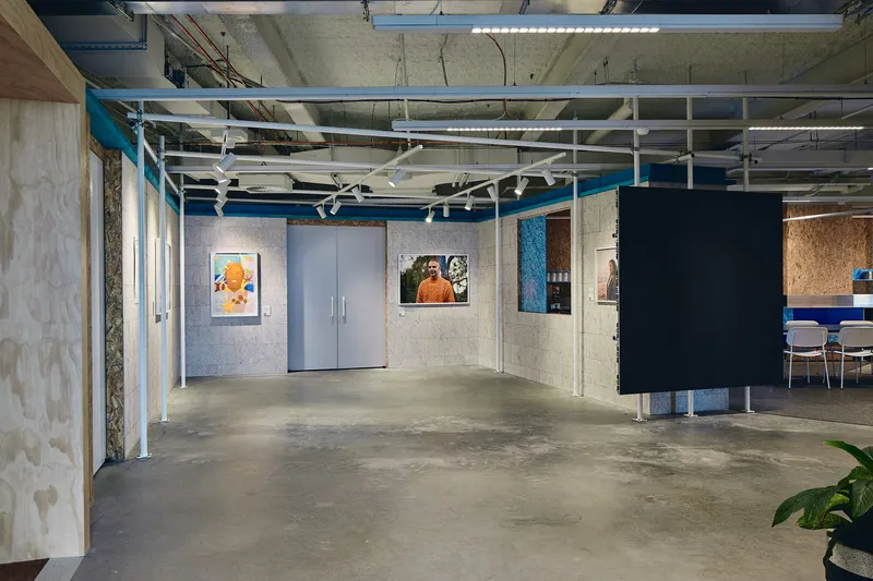Open corridor with concrete block walls displaying artwork and polished concrete floors under exposed steel beams