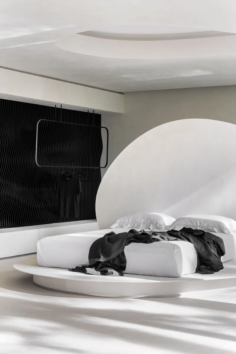 Oblique view of the rounded headboard niche and ribbed black accent wall in soft daylight