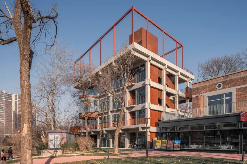 Street facade with exposed concrete columns at ground level and weathered steel cladding on upper floors in winter