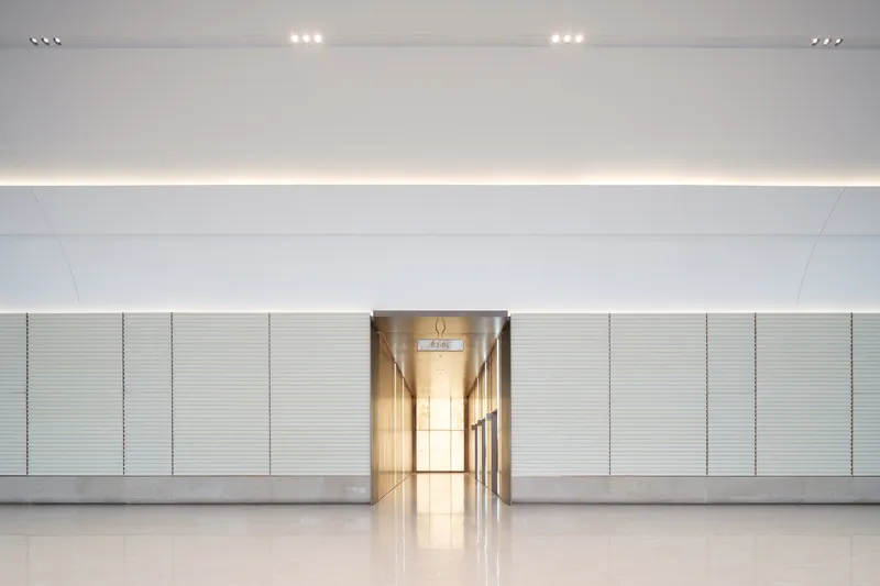 Interior corridor wall with horizontal ribbed panels and illuminated central passage through the recessed lighting