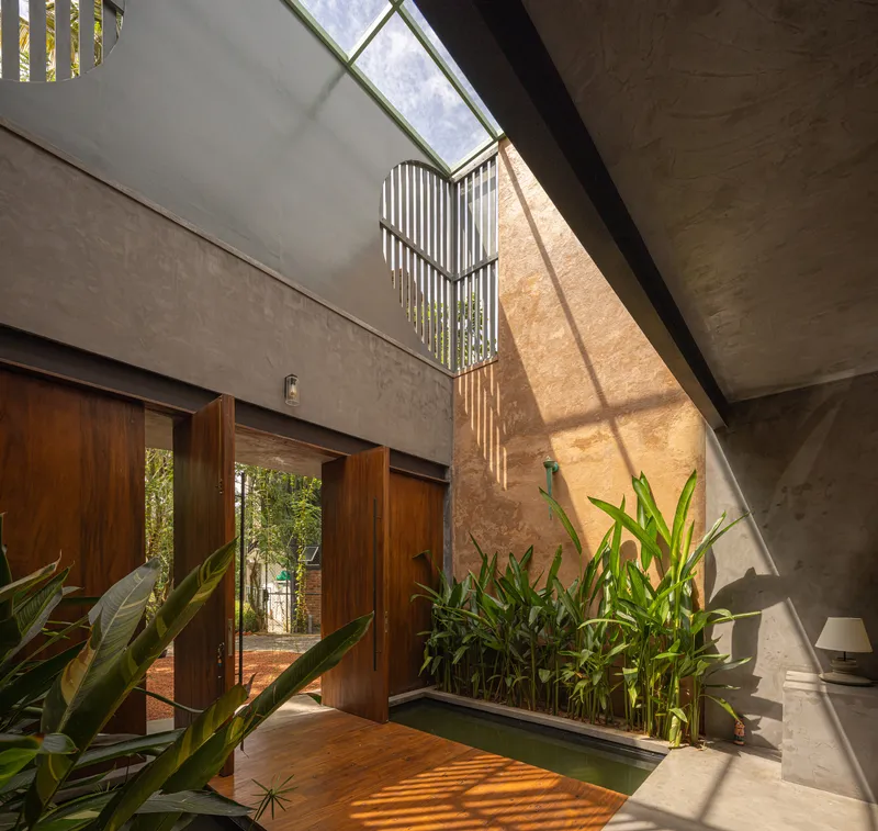 Double-height entryway with glazed clerestory creating dappled light patterns on the ochre wall