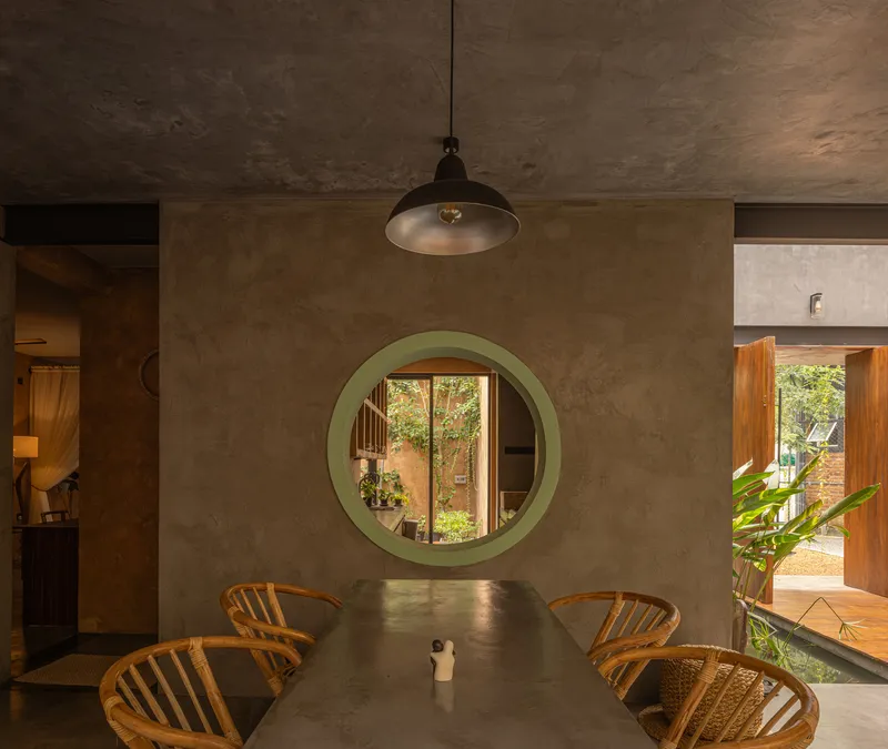 Dining area with circular green portal opening to a planted courtyard beyond