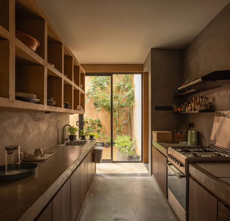 Galley kitchen with timber shelving and glazed door opening to a small garden courtyard