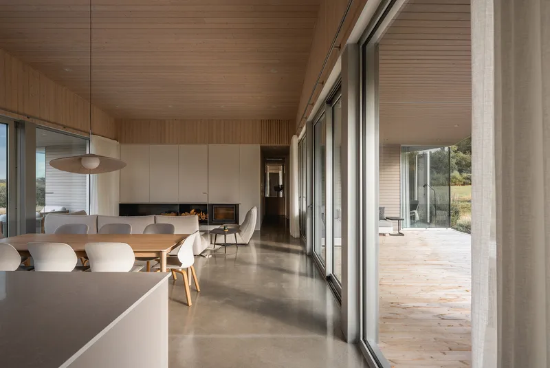 Open living space with polished concrete floor and timber ceiling viewed toward the glazed terrace opening