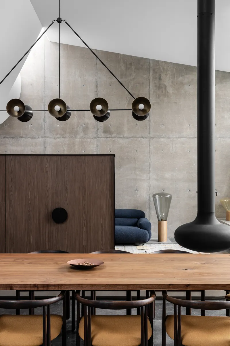 Pendant light fixture with disc-shaped shades suspended above timber dining table and concrete wall