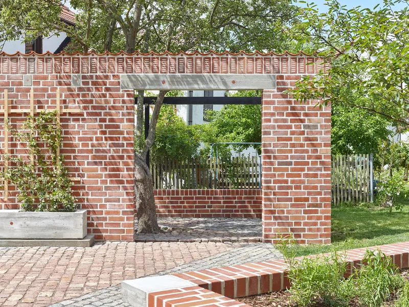 Brick garden portal framing existing tree with concrete lintel and cobblestone paving underfoot