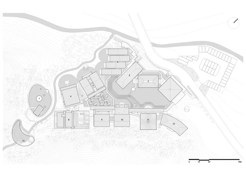 Site plan drawing showing multiple rectangular volumes arranged across sloping terrain with topographic contours and pathways