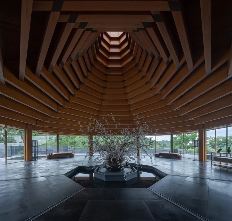 Stepped timber ceiling coffers radiating upward around a central skylight above a sculptural branch arrangement