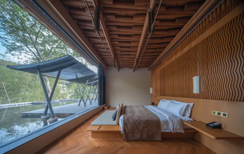 Guest room with herringbone wood flooring, wavy timber wall paneling, and exposed timber beam ceiling