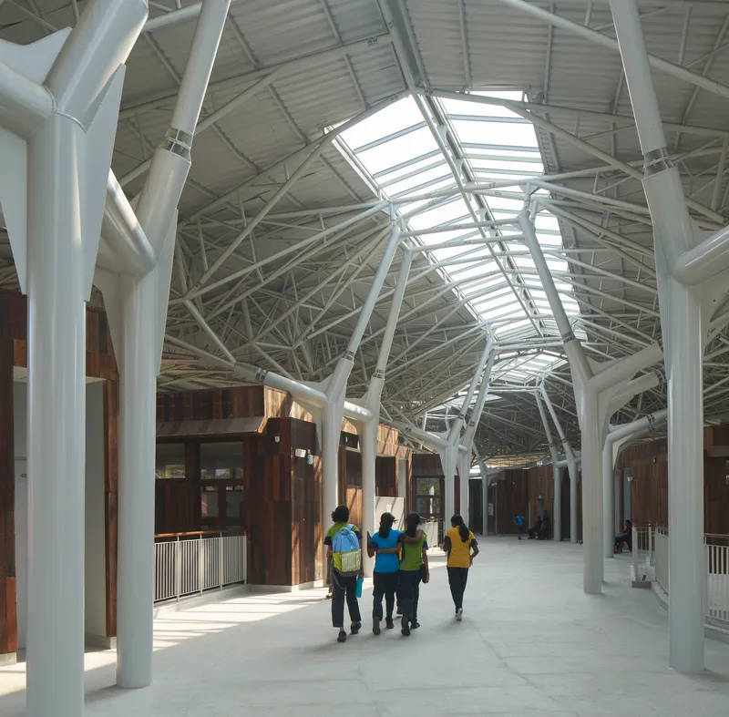 Interior circulation corridor with white structural trusses, skylights, and visitors walking past timber pavilions