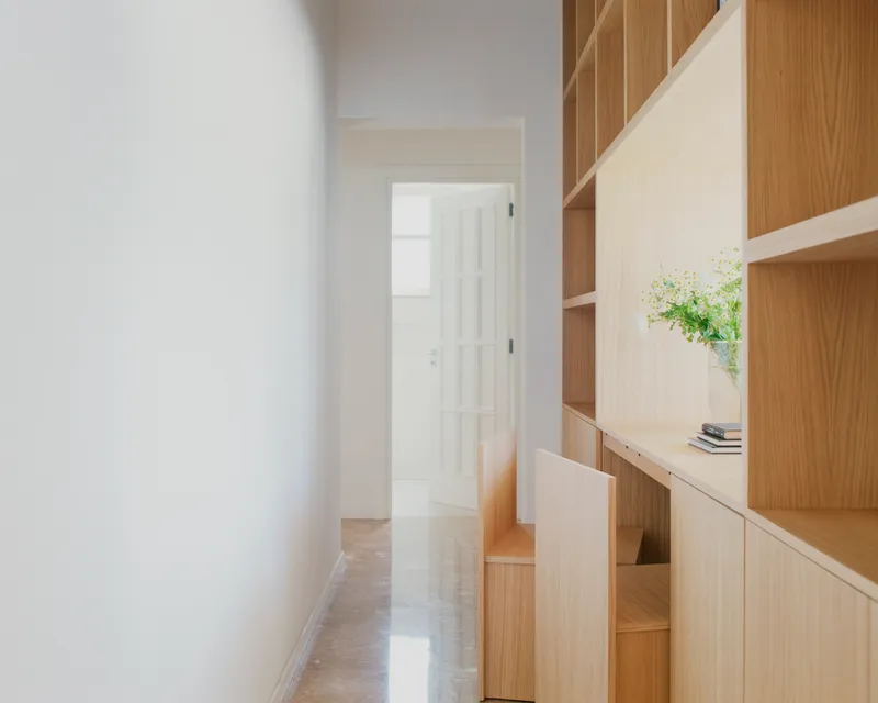 Corridor with floor-to-ceiling oak shelving and cabinetry leading to a glazed door at the end