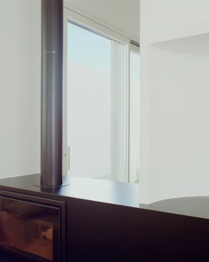 Black wood-burning stove beside sliding glass door overlooking a muted sky