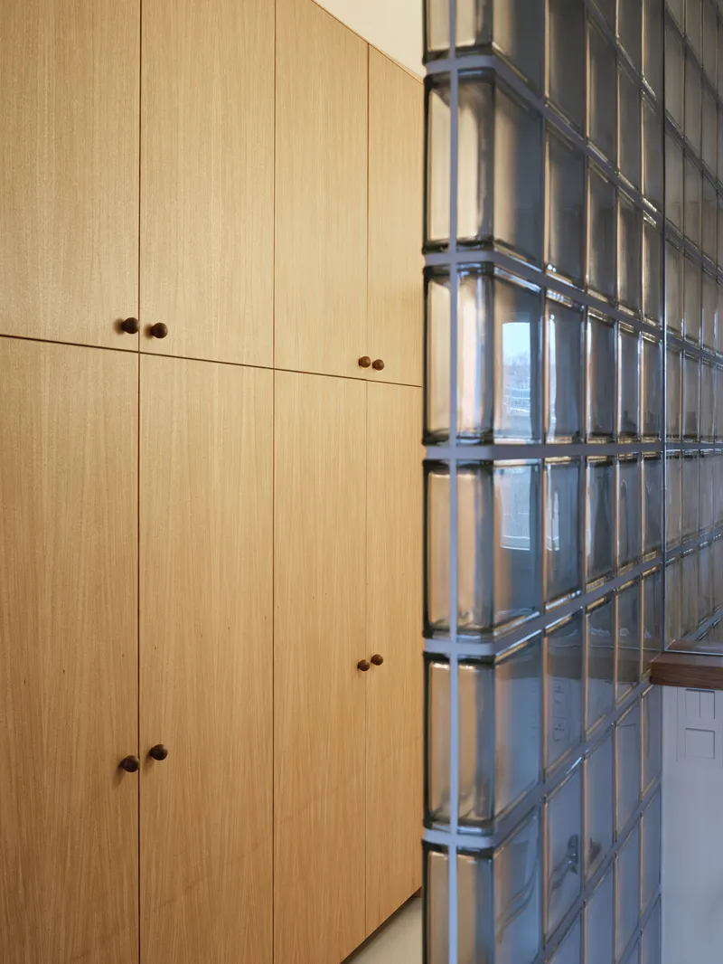 Corner junction of oak cabinet wall and glass block partition with steel frame
