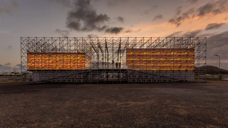 Scaffolding structure with illuminated orange panels at the center captured at dusk