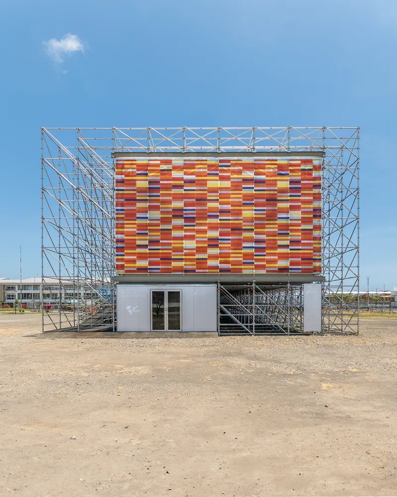 Frontal view showing the entrance volume beneath the multicolored striped panel facade under clear sky