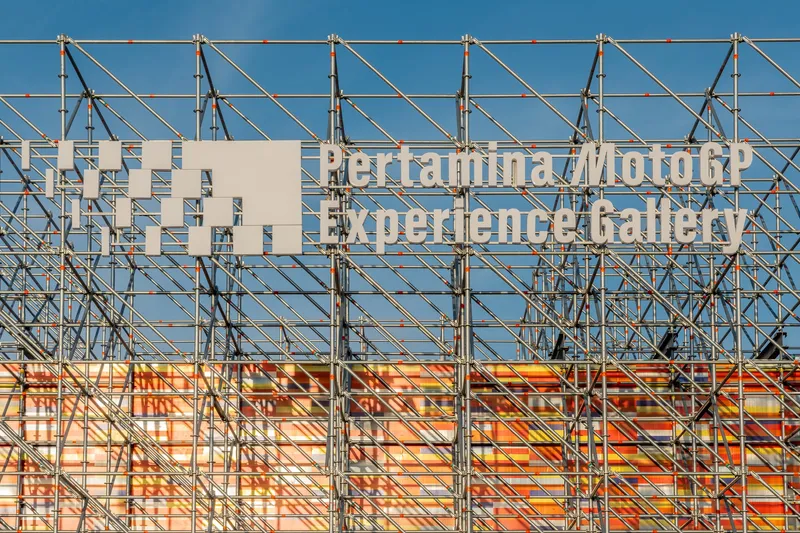 Close view of steel truss framework above the colored panel screen against clear blue sky