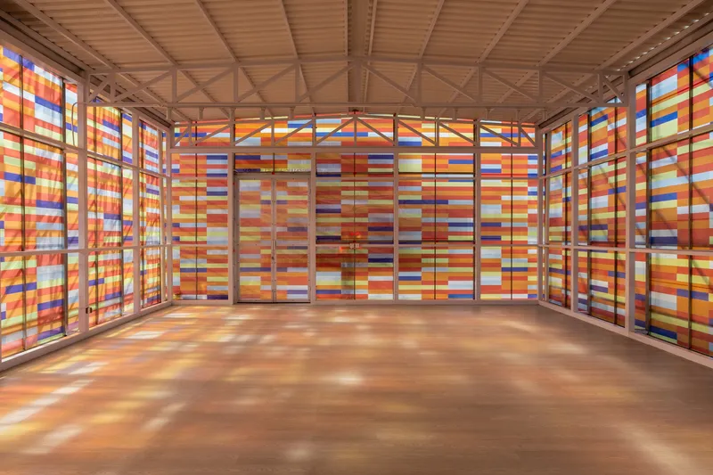 Interior space with colored light filtering through the striped translucent panels onto polished concrete floor