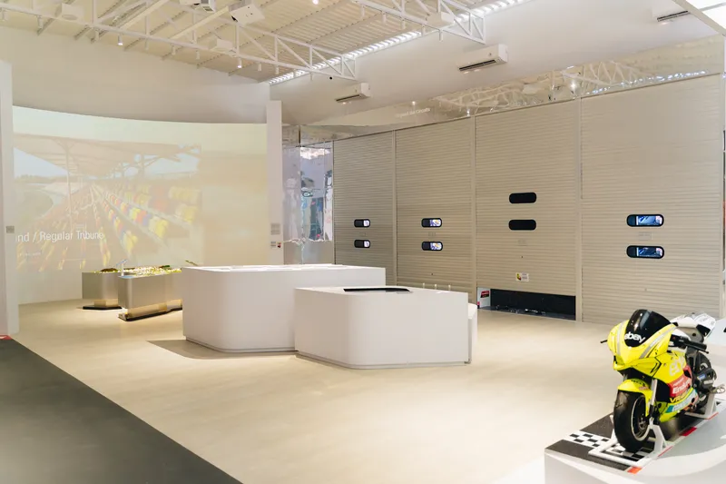 Interior showroom with curved white display counters and horizontal wood slat walls under track lighting