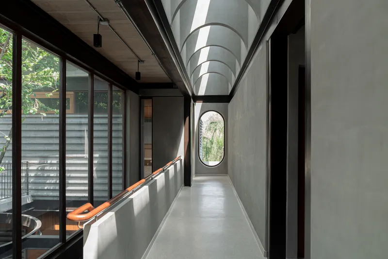 Concrete corridor with arched ceiling and oval window at the far end