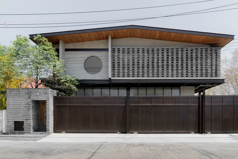 Street facade with woven brick screen on the upper level and dark metal gate panels below