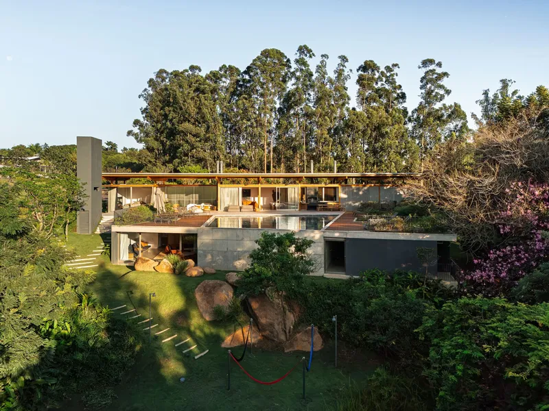 Two-story residence with timber roof cantilevering over glass walls and a terrace edged by tall eucalyptus trees