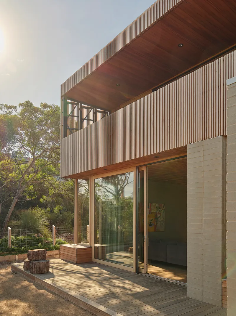 Exterior view of timber deck terrace with vertical slatted facade and cantilevered wood soffit above