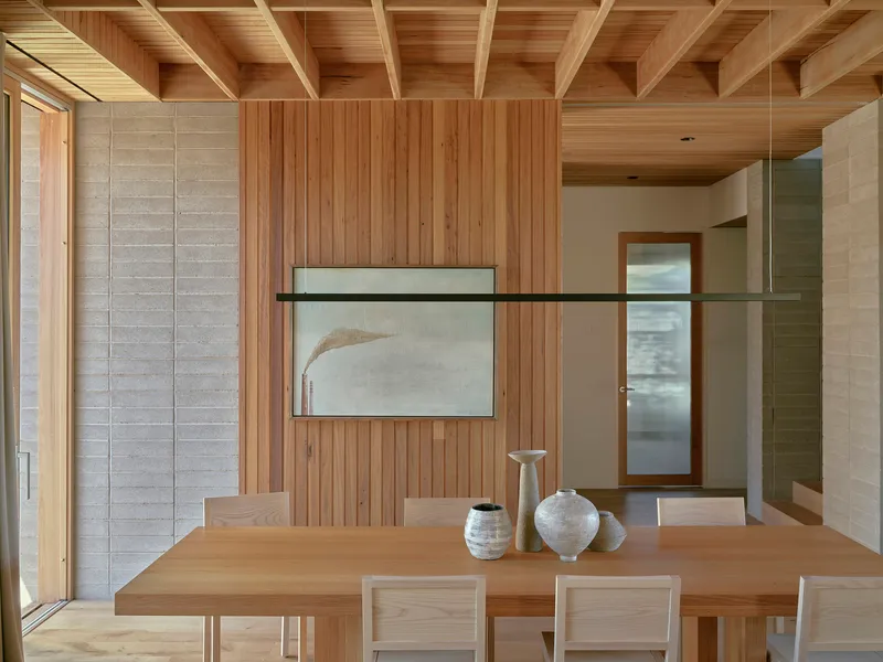 Dining area with timber-clad walls and exposed beam ceiling beneath a suspended linear light fixture
