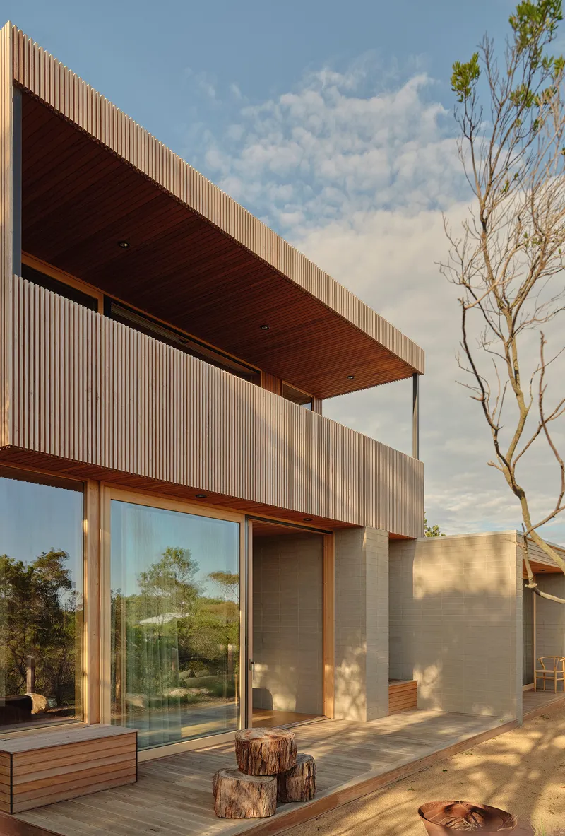 Corner terrace with cantilevered timber soffit and glass sliding doors framed by tree stumps