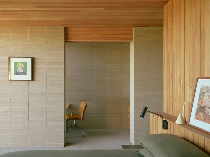 Recessed nook with rammed earth walls and timber soffit viewed from adjacent living space