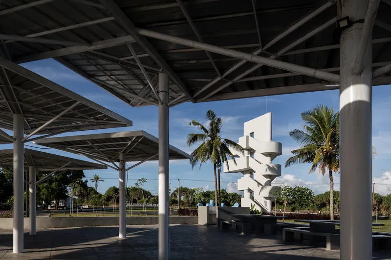 View from beneath the gridded steel canopy toward the white spiraling tower and palm trees