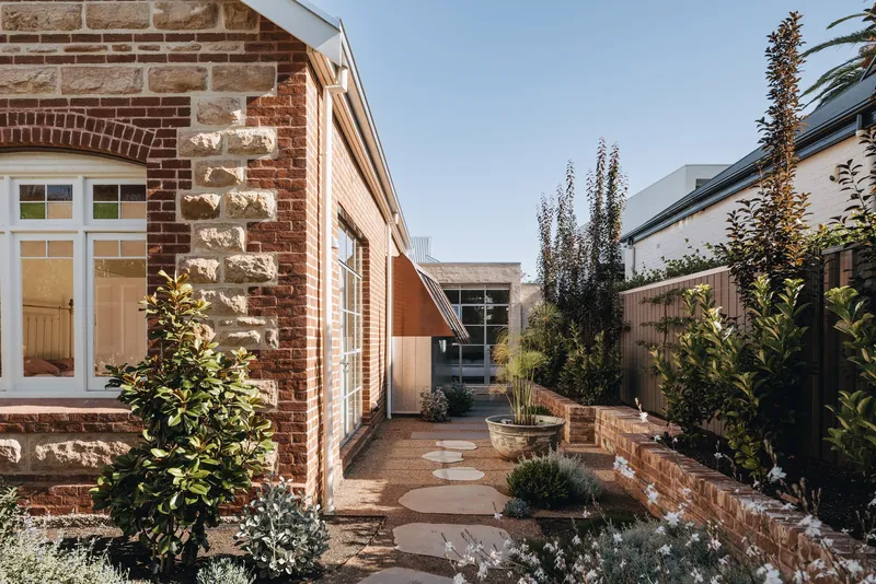 Side courtyard with stepping stone path between planted beds and brick retaining walls