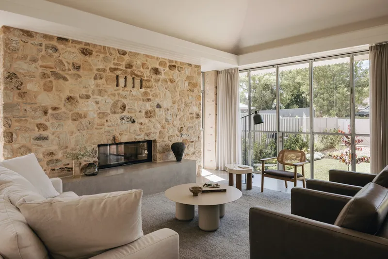 Living room with stone fireplace wall and floor-to-ceiling glass doors overlooking the garden