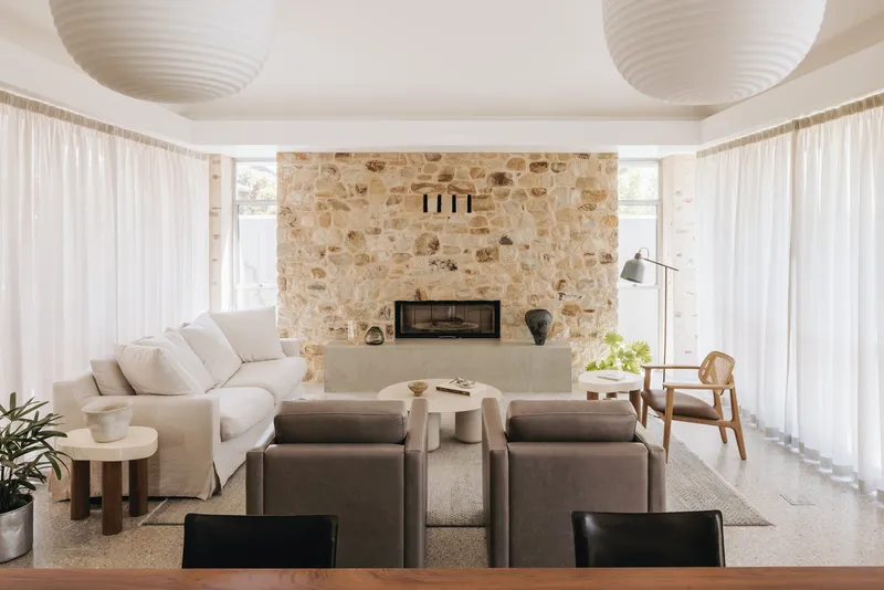 Living room with sandstone fireplace wall flanked by sheer curtains and two paper lanterns overhead
