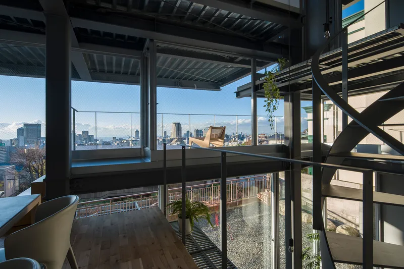 Interior view through steel framing toward the glazed facade and planted rooftop terrace beyond