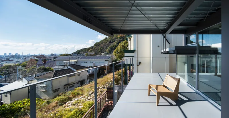 Rooftop terrace with steel canopy, timber bench, and planted green roof overlooking the hillside neighborhood