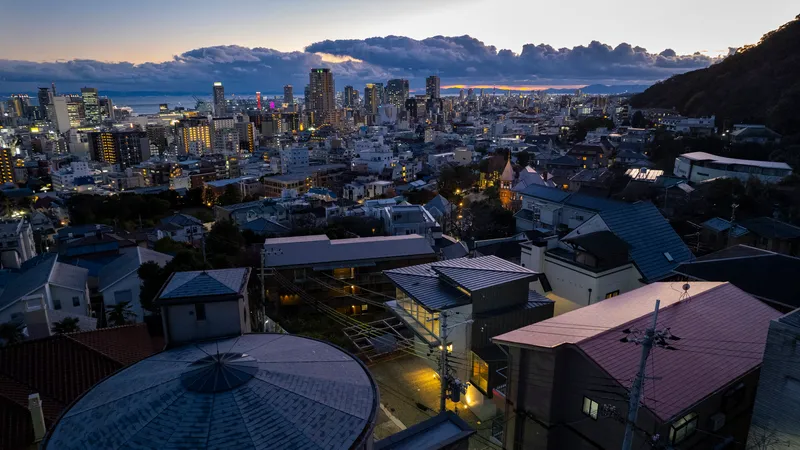 Aerial view of residential volumes with varied metal roofs nestled in a hillside neighborhood at dusk