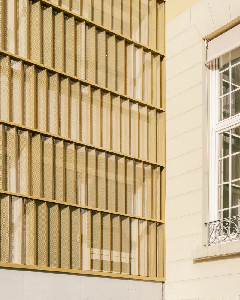 Exterior detail of vertical timber slat facade panels meeting a white horizontal-board wall