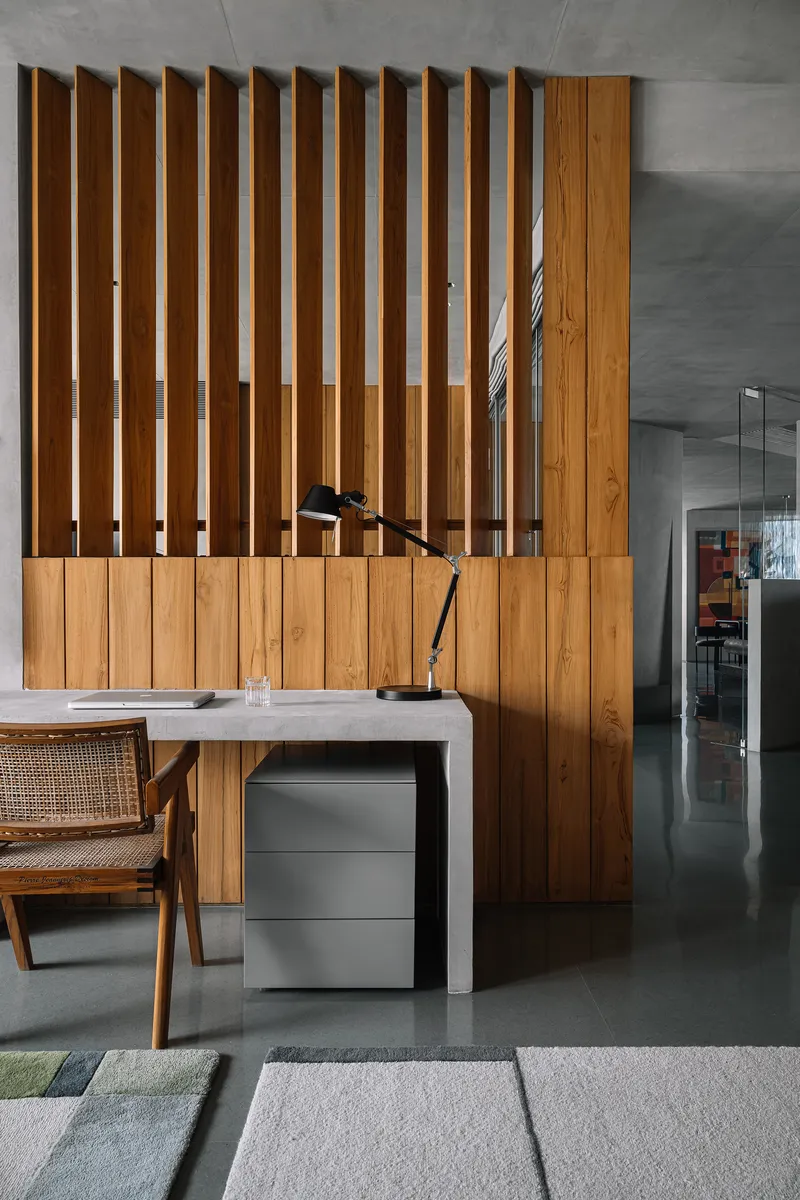 Workspace with timber slat screen divider and concrete desk below exposed ceiling