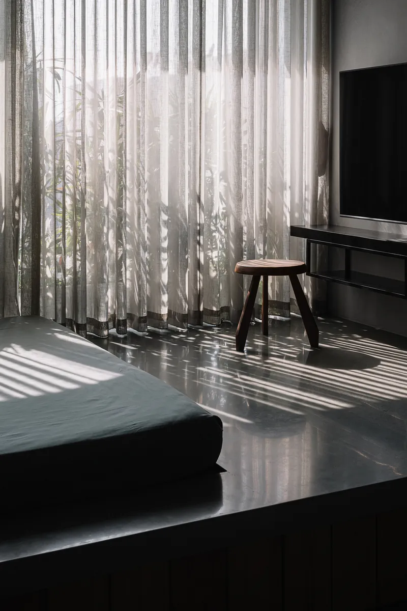 Polished floor reflecting striped shadows cast by sheer curtains filtering afternoon sunlight
