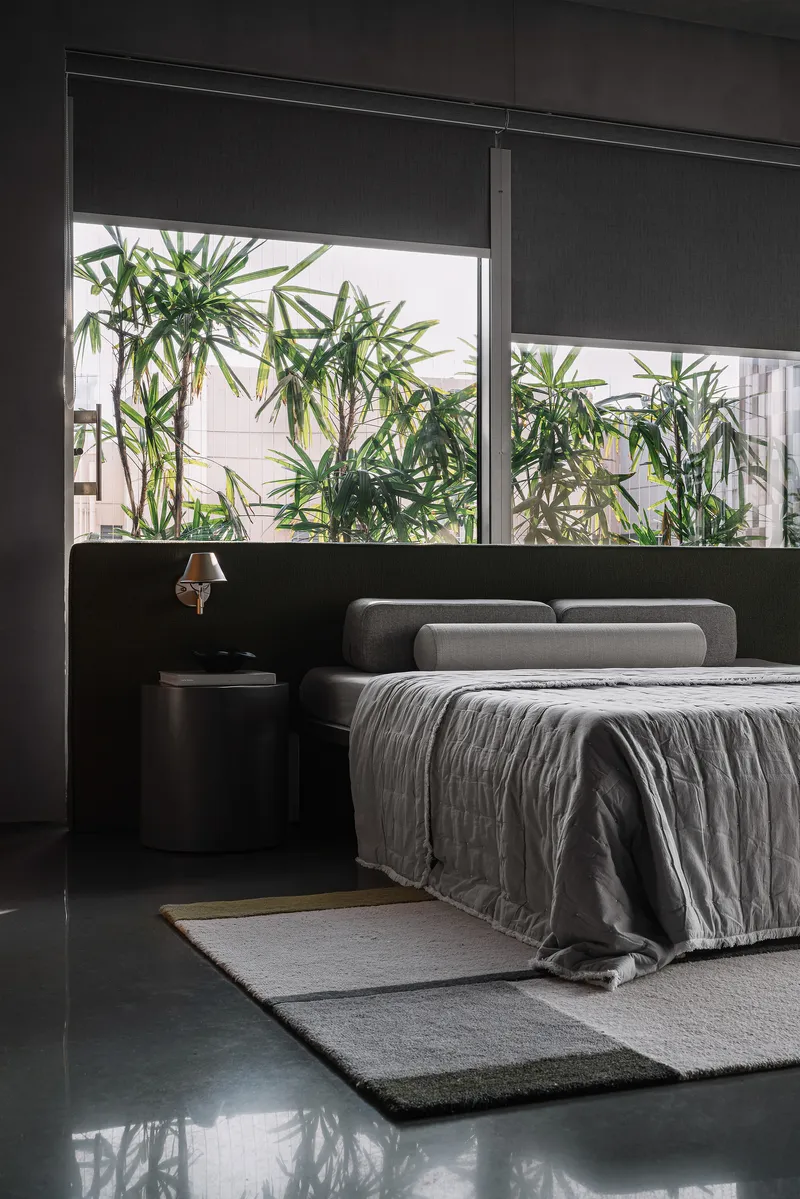 Bedroom with horizontal window framing bamboo plants in an adjacent courtyard